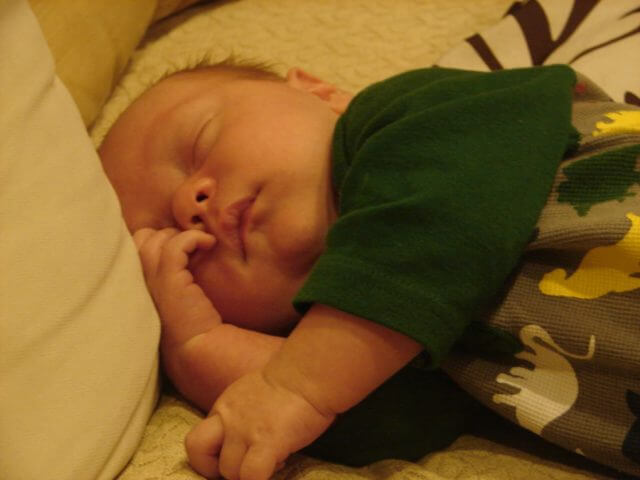 An infant laying down with their eyes closed.