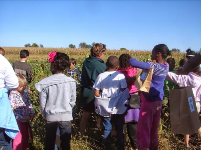 A group of people mills about in front of a field