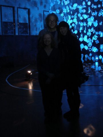 The teacher, lighting artist, and volunteer organizer of the art piece standing in front of it